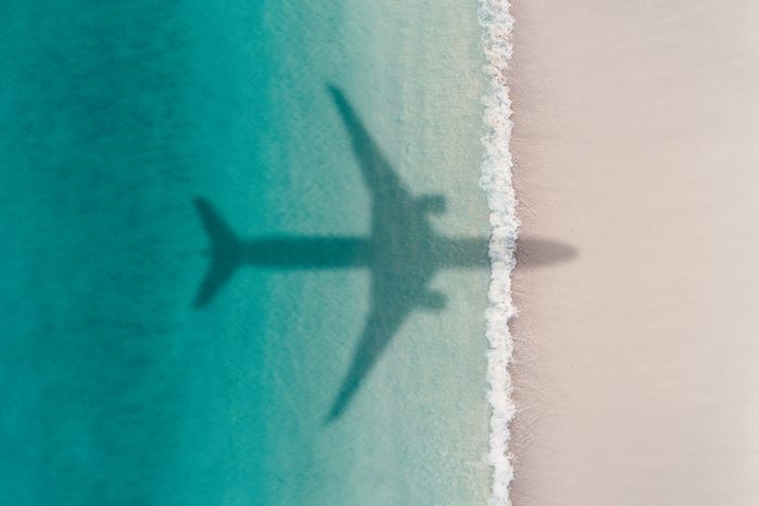 Aerial shot showing an aircraft shadow flying over a beach