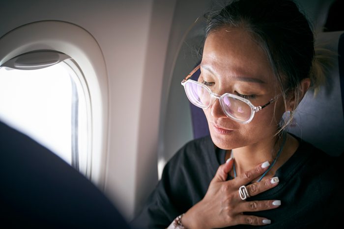 asian female air passenger feeling uncomfortable on flight