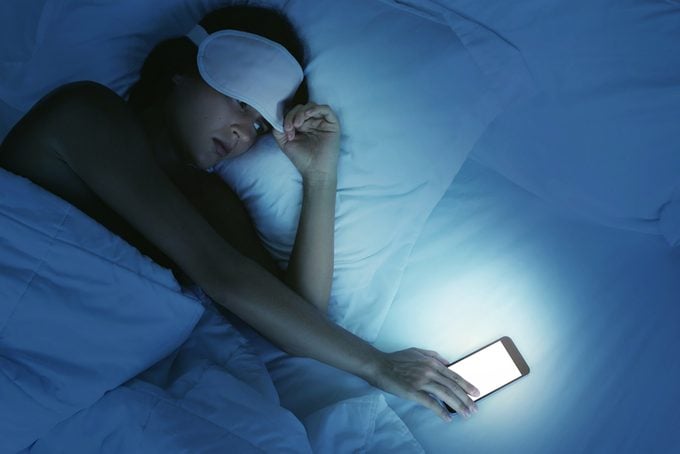 Woman lying in the bed and looking on smartphone at night
