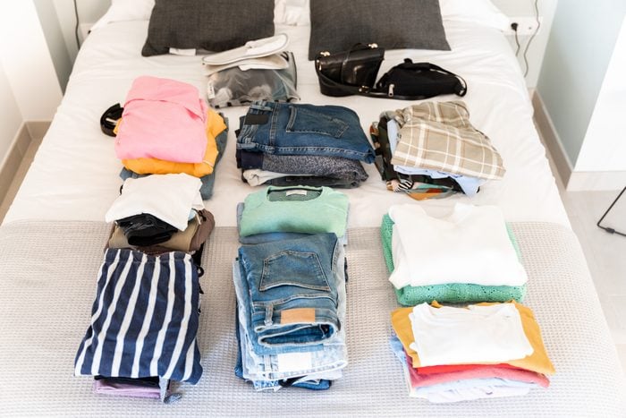 Women's clothes folded over the bed, ready to store in the suitcase.