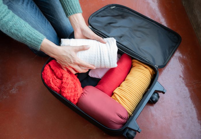 Woman open her suitcase for pack and arranging cloths for travelling on holiday period.