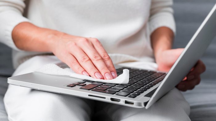 Midsection Of Woman Cleaning laptop keyboard with a cleaning cloth
