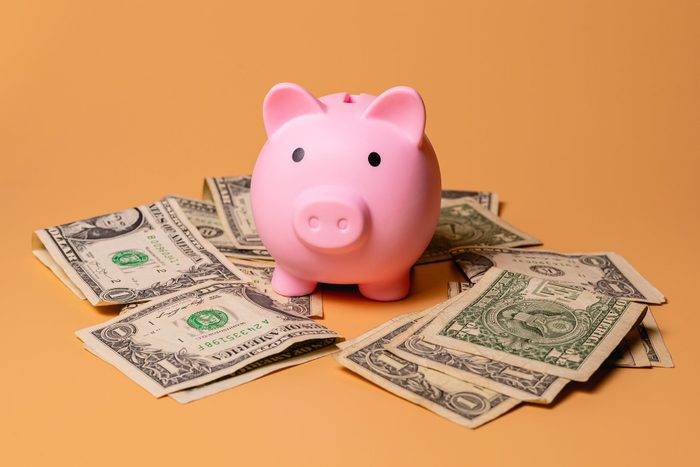 A piggy bank with US dollar bills isolated on an orange color background in studio photo. Finance and economy concept.