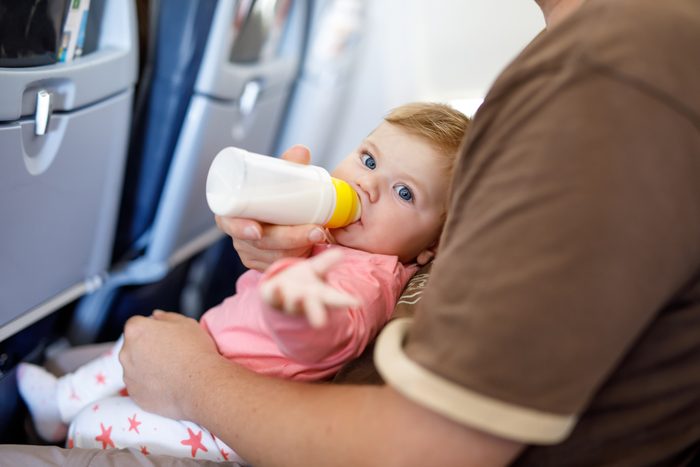 Dad holding his baby daughter during flight on airplane going on vacations