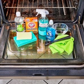 cleaning supplies arranged on open glass oven door