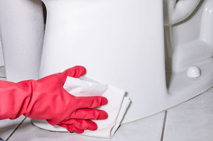 gloved hand cleaning the exterior of a toilet