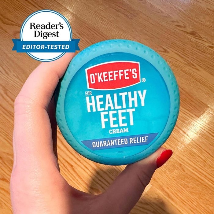Hand holding a container of Healthy Feet Cream