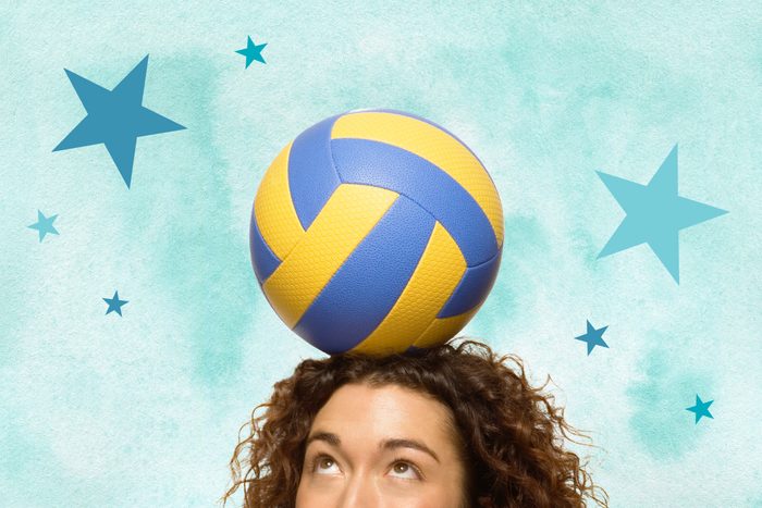 Woman looking at volleyball balanced on her head