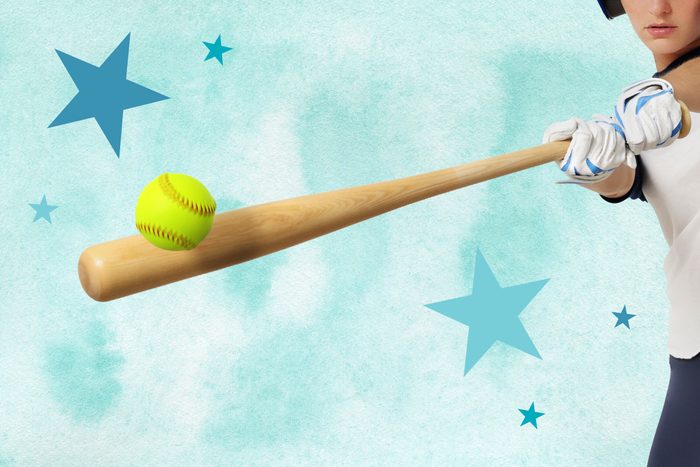 Woman holding a wooden bat hitting a softball