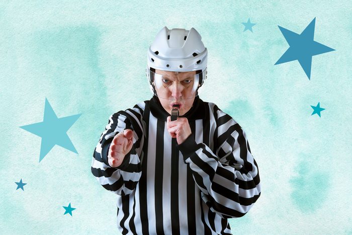 Ice hockey referee blowing whistle and pointing with hand
