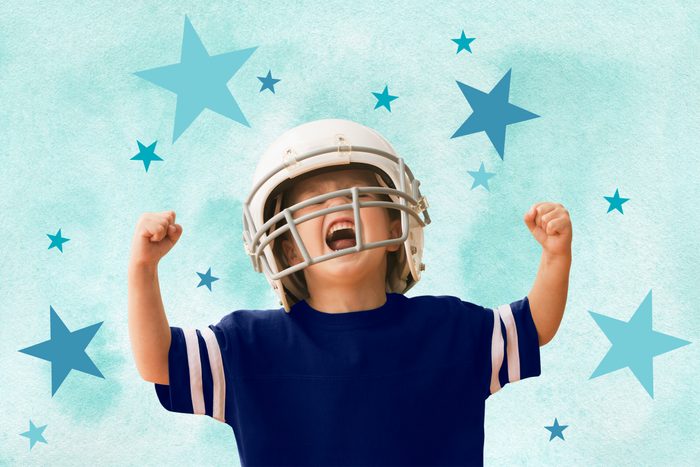 Boy wearing a football helmet cheering with fists clenched