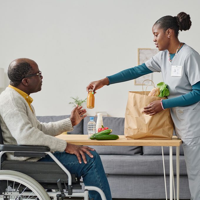 Nurse handing food to a man in a wheelchair