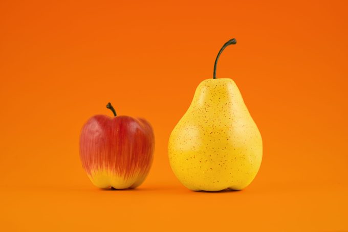 red apple next to yellow pear on orange background