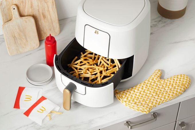 mcdonalds fries in the basket of an open air fryer on a kitchen counter