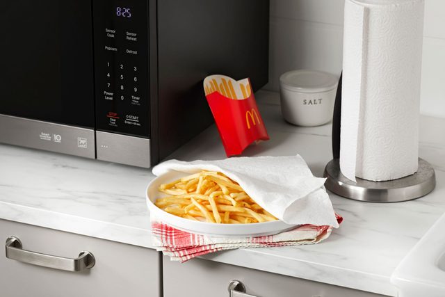 plate of mcdonalds french fries on a plate with a paper towel near a microwave