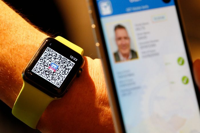 A person scans a QR code on an Apple Watch to temporarily send their digital driver's license to another mobile phone