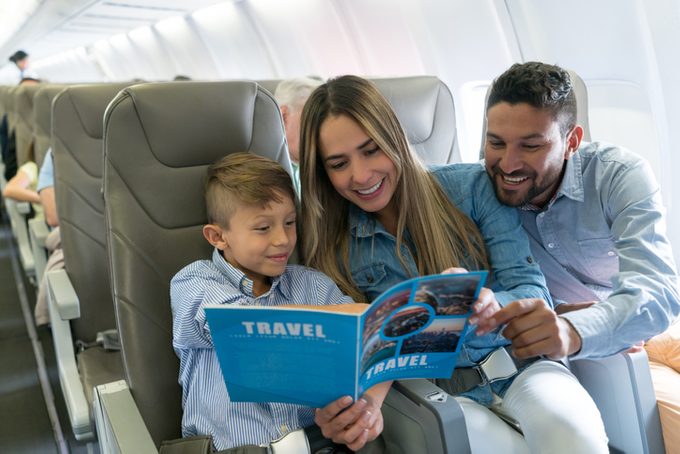 Family traveling by plane and reading a travel guide