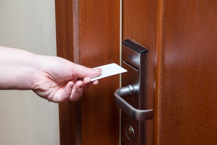 Female hand putting key card switch in to open hotel room door. Holding magnetic card for door access control scanning key card to lock and unlock door