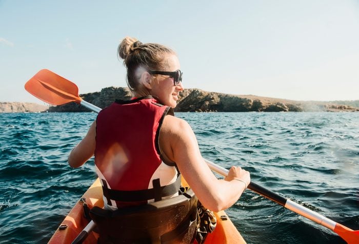 Rear view of mid adult woman sea kayaking, Menorca, Balearic islands, Spain