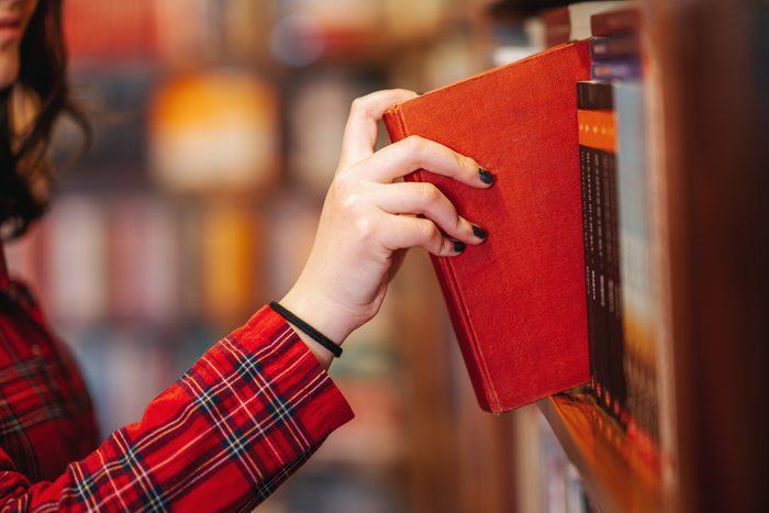 hand taking a book from a bookshelf