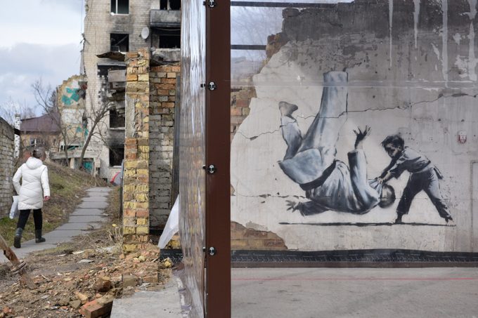 A woman walks near the graffiti art of the artist Banksy...