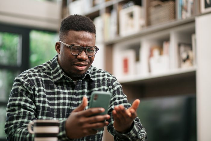 Young African American man having reading bad news on his smart phone