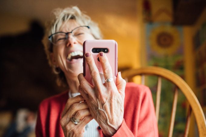 Senior woman laughing while using her smartphone