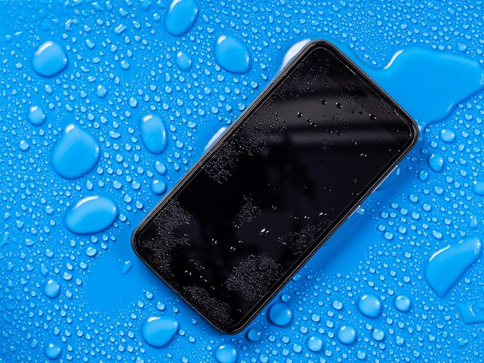 Mobile phone with water drops on a blue background