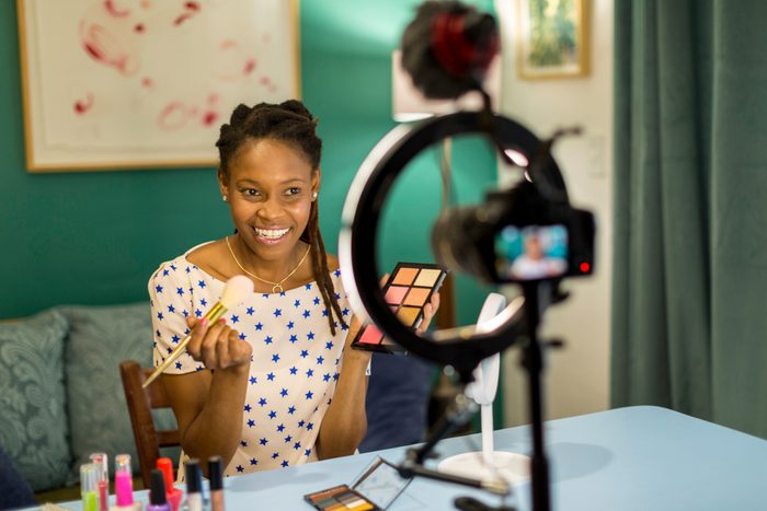Young Black woman filming a beauty and makeup vlog in an unknown room of a residential home