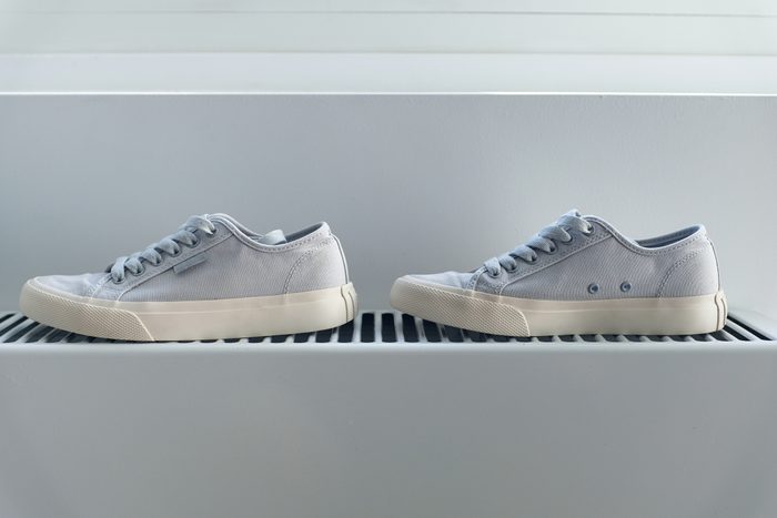 New clean modern sneakers for a woman, teenager or girl. Shoes are dried on a battery or a heating radiator after washing, at home or indoors. Clothing care. A fashionable and stylish lifestyle. A copy of the text space.