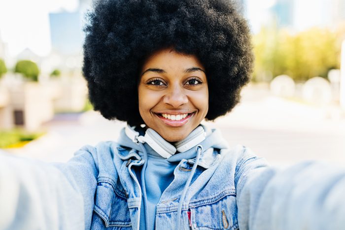 Happy young afro woman taking selfie with mobile phone outdoors