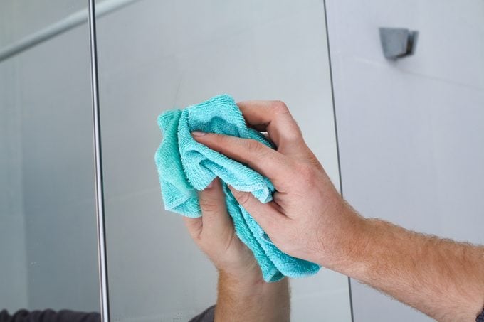 A man wipes a mirror cabinet in the bathroom with rag. Cleaning of the house, bathroom.