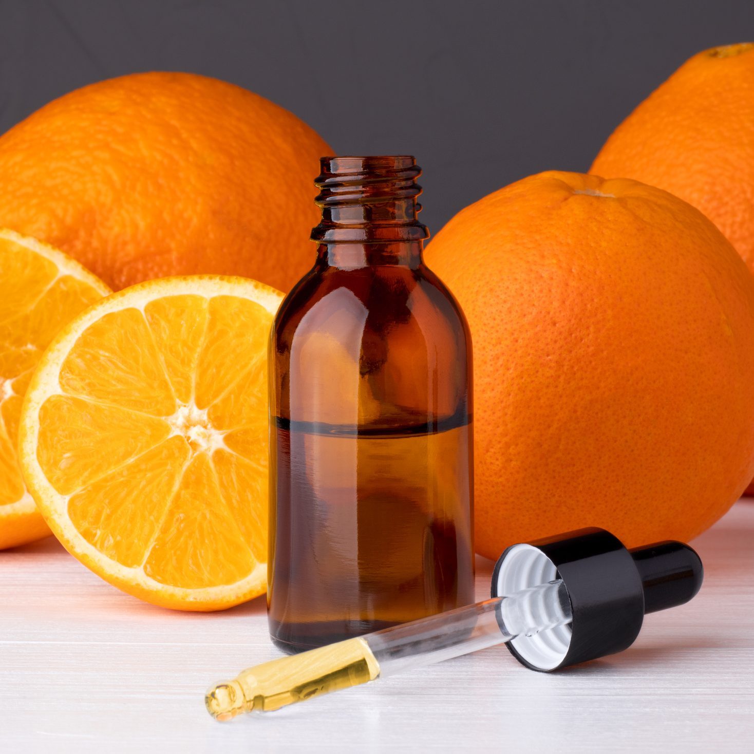 Bottle with essential oils, dropper with oil. Fresh oranges.
