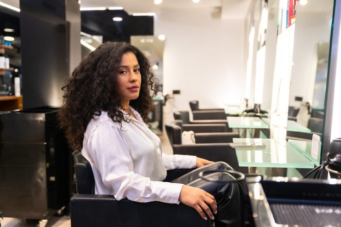 Modern luxury hairdressing salon, female client with curly hair sits waiting to be served by the hairdresser