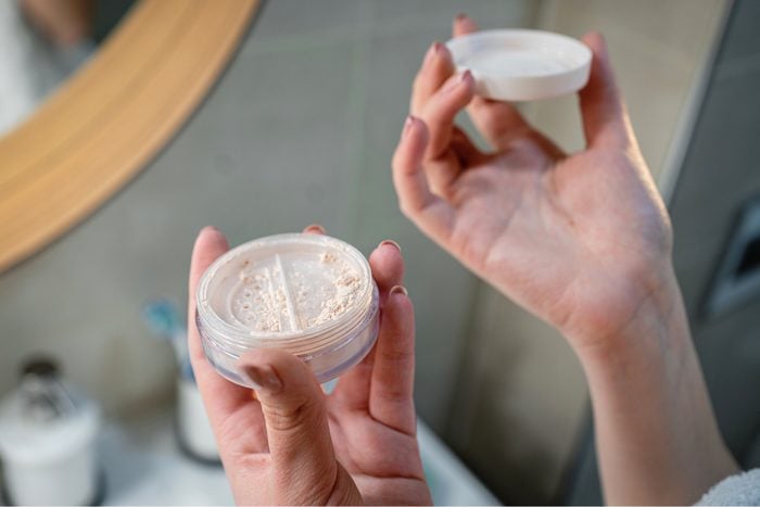 Close up of woman holding face powder in bathroom