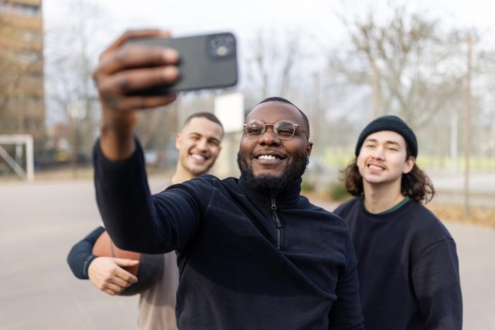 Smiling basketball player taking selfie with friends