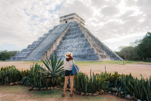 Rear view of woman standing on the background of Chichen Itza pyramid in Mexico