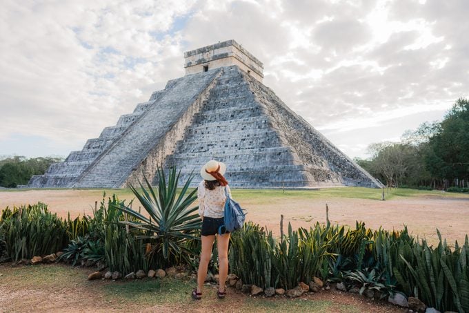 Rear view of woman standing on the background of Chichen Itza pyramid in Mexico