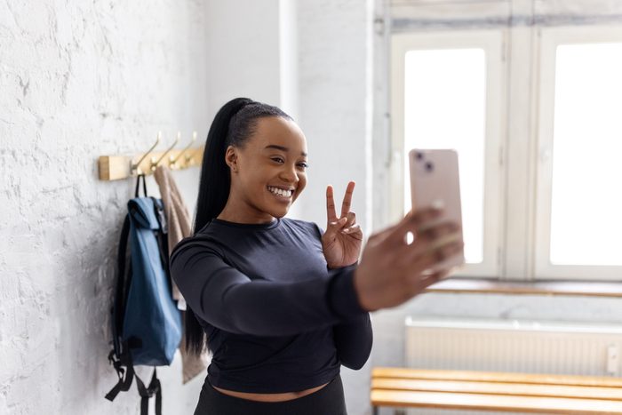 Young African woman taking selfies in the dressing room at gym
