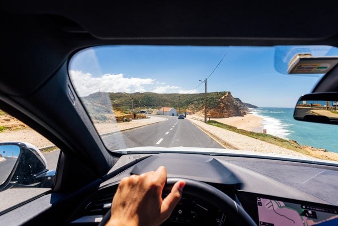 Personal perspective point of view of a man driving along the Atlantic coast in Portugal