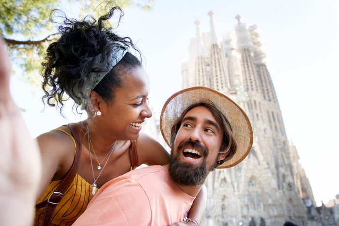 A happily just married couple taking a selfie with the Sagrada Familia behind.
