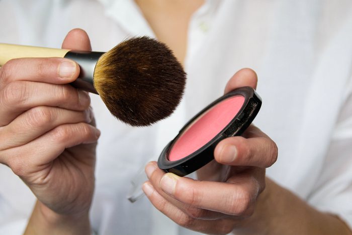 Close up of woman holding blush and makeup brush