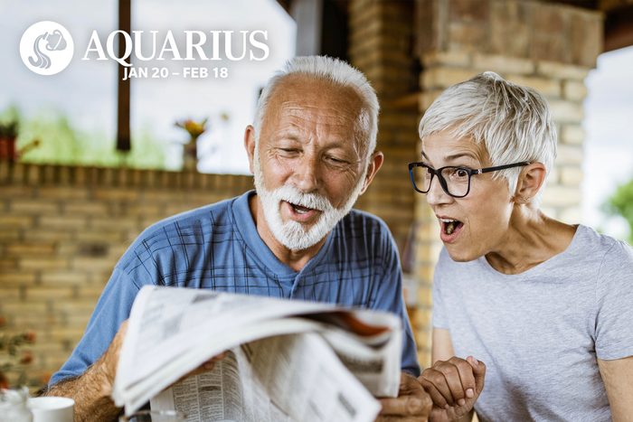 Surprised senior couple reading newspapers during breakfast