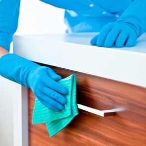 Woman Cleaning Kitchen Cabinets with cleaning gloves and cloth