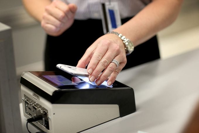 woman passes her iphone over a scanner as she uses the new mobile app for expedited passport and customer screening