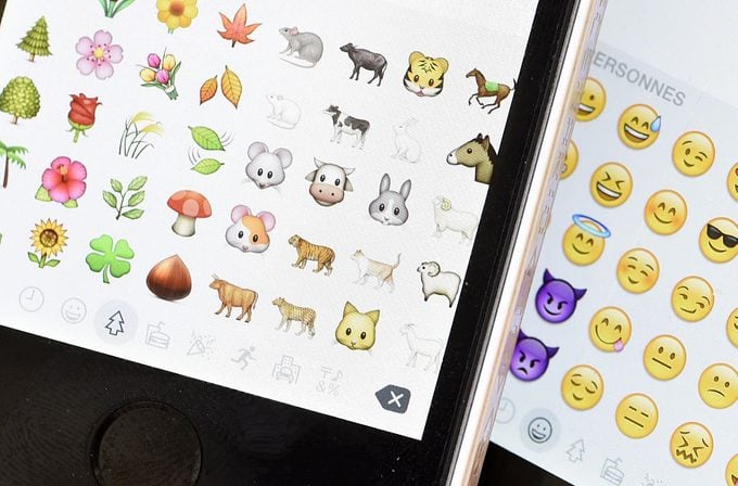 Emoticons on the screens of two mobile Apple iPhones in Paris