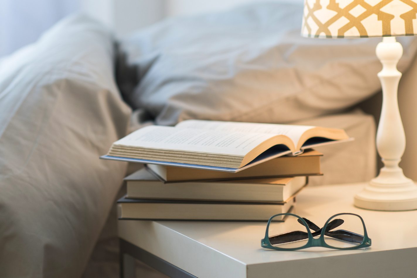 USA, New Jersey, Bed with lamp, books and glasses on bedside table