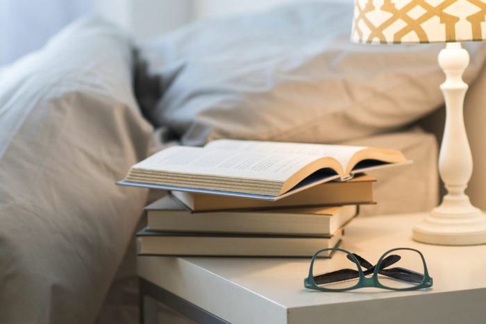 USA, New Jersey, Bed with lamp, books and glasses on bedside table