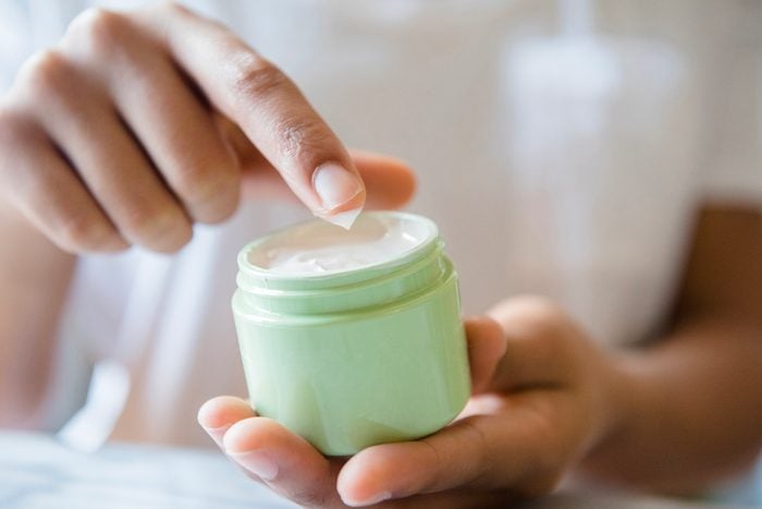 Close up of woman dipping finger in lotion jar