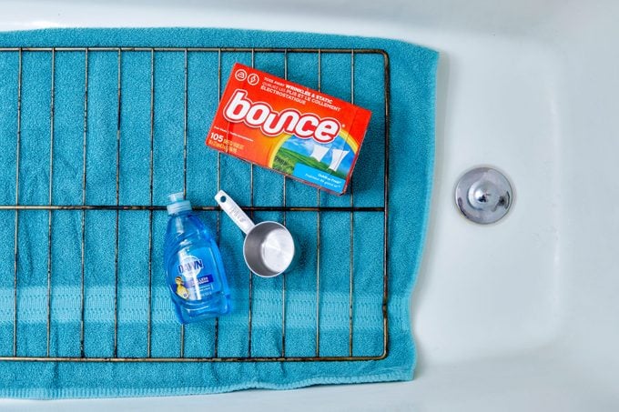 oven rack and cleaning supplies laid out in a bathtub